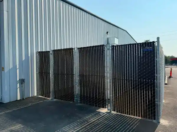 Brown Viewguard privacy slat chain link and double gates at a white metal commercial building
