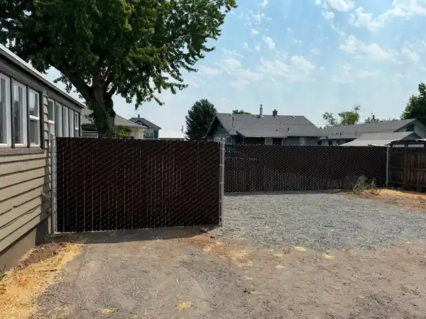 Brown Viewguard privacy chain link enclosing a gravel back lot