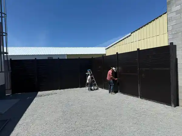 L S Fencing crew assembling tall steel privacy fencing on site