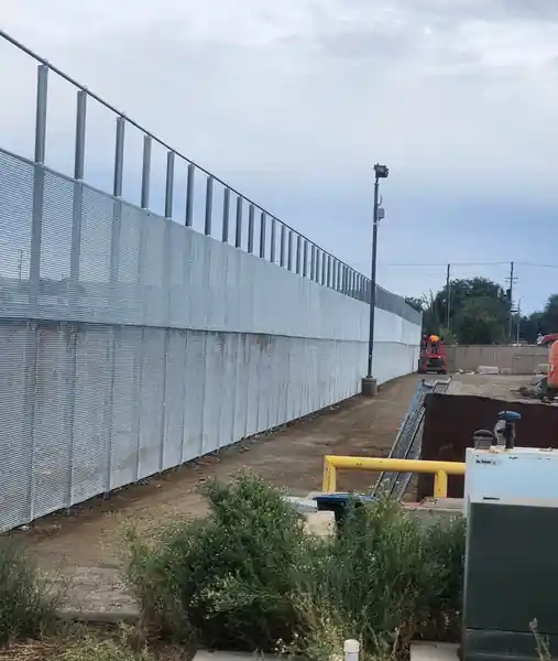 A long, tall chain-link wall with mesh screening built by the L S Fencing crew
